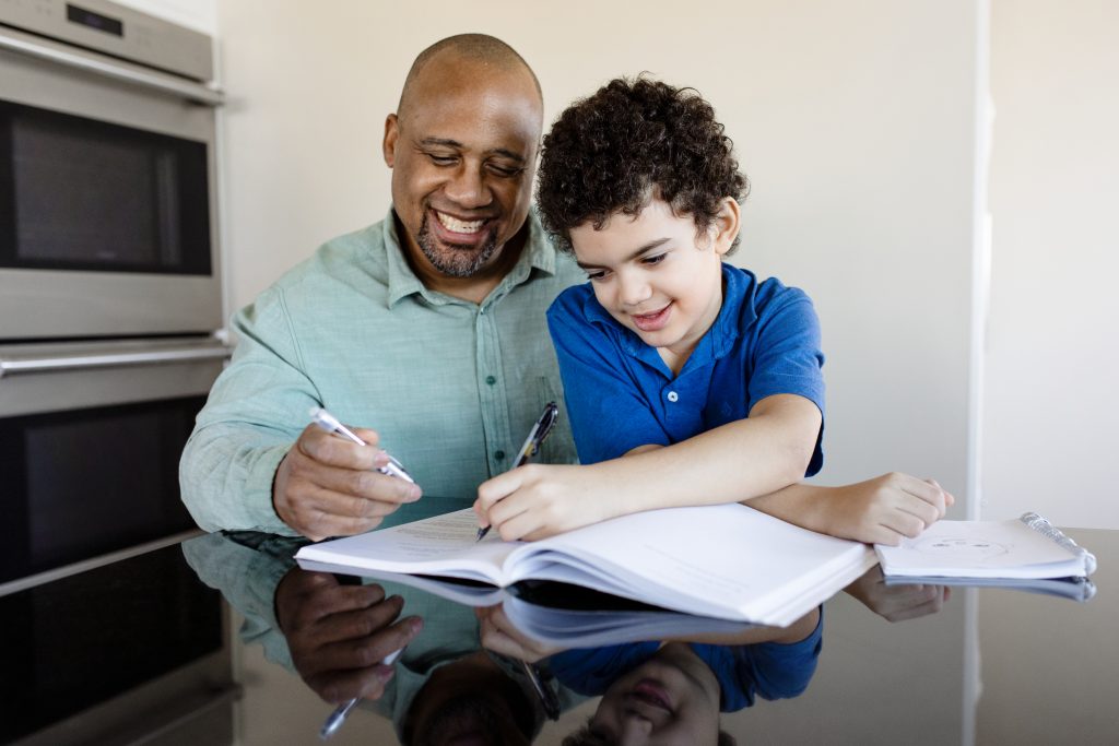 Homem com filho no colo aprendendo sobre controle financeiro