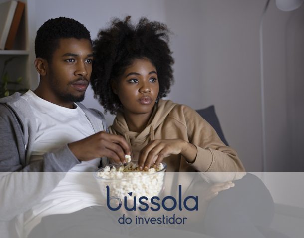 Casal assistindo a um programa de TV sobre finanças e investimentos