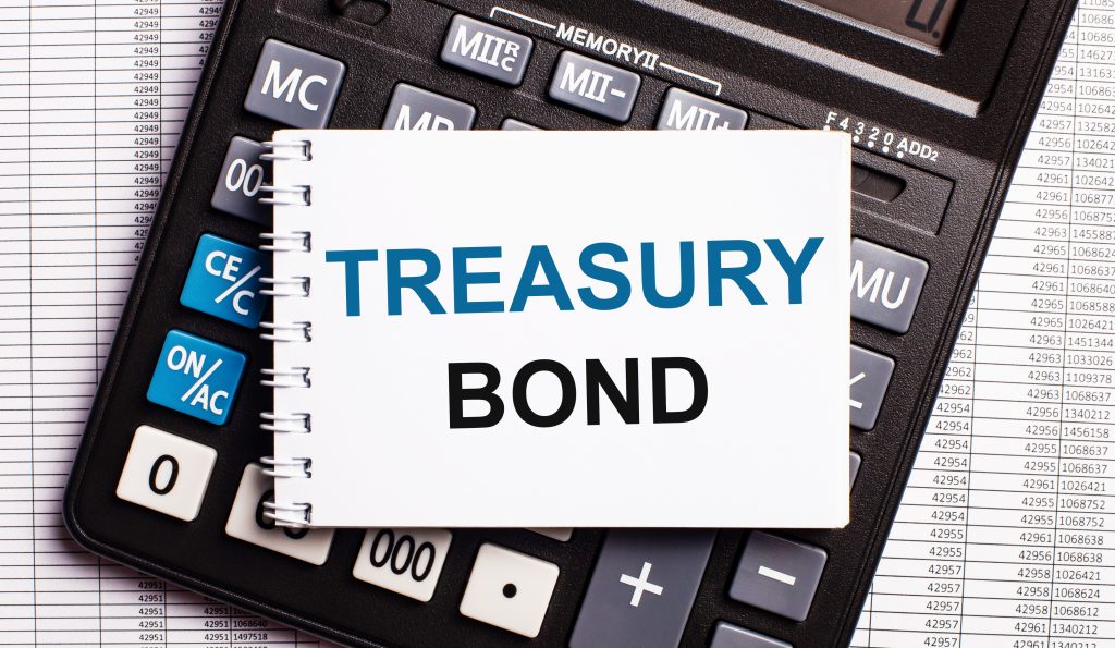 Em uma mesa, há uma Calculadora com um papel em cima escrito Treasury Bonds, que são um tipo de renda fixa no exterior